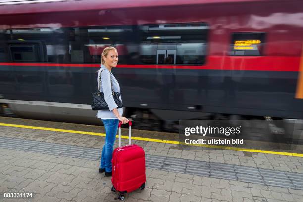 Eine junge Frau wartet auf einen Zug in einem Bahnhof. Zugfahrt in den Urlaub