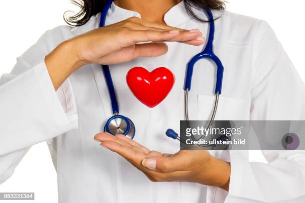 Eine junge Ärztin hält ein Herz symbolisch in der Hand.