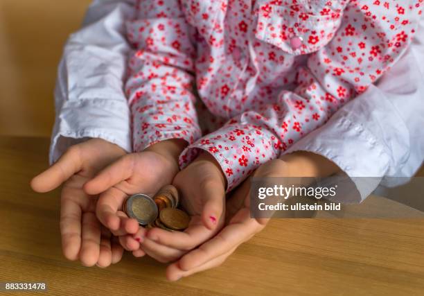 Kinder halten Münzen von Geld in ihren Händen. Symbolfoto für Sparen und den Umgang mit Geld lernen.