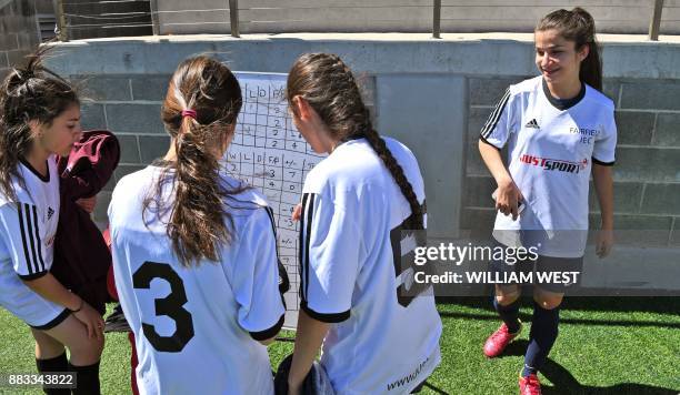 Photo taken on September 14 shows refugee Sarah Glaoo aged 17, checking the table with teammates after a football match organised by Football United,...