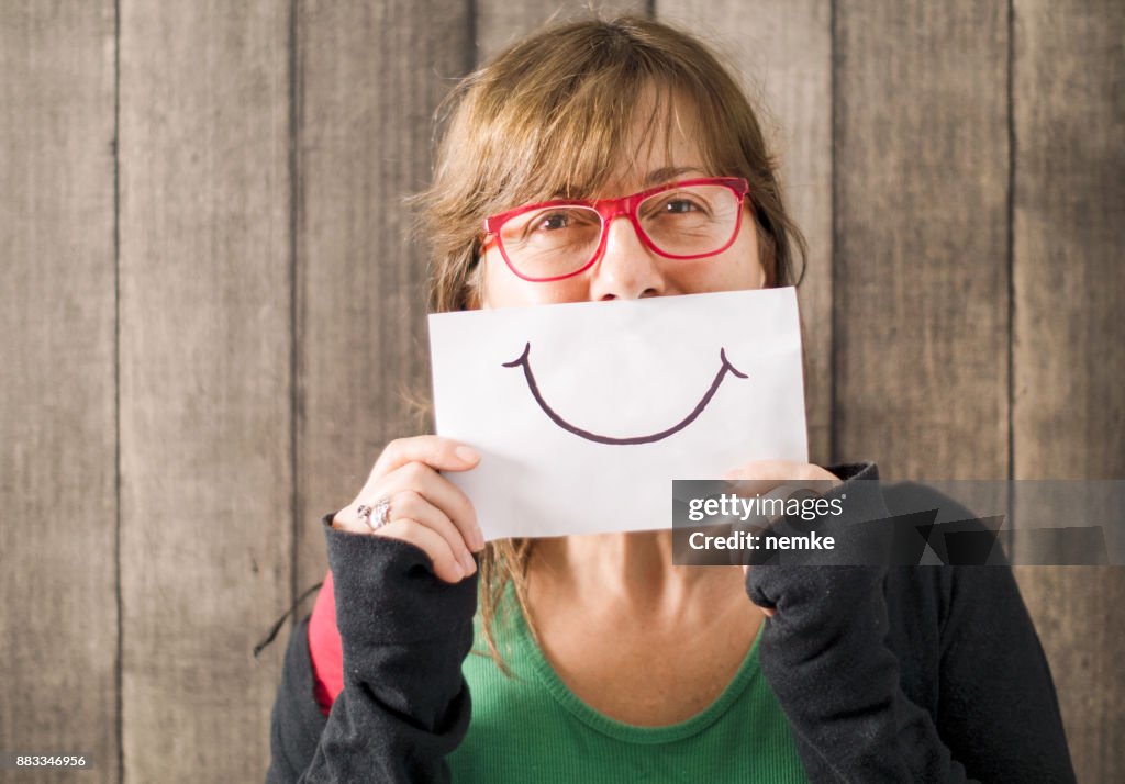 Mature mid age woman with a smile painted on paper