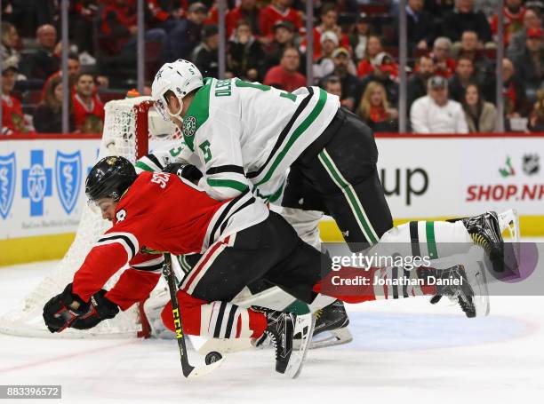 Nick Schmaltz of the Chicago Blackhawks is shoved to the ice by Jamie Oleksiak of the Dallas Stars at the United Center on November 30, 2017 in...