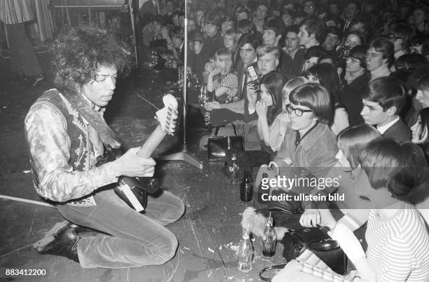 Der US-amerikanische Rock-Gitarrist und Sänger Jimi Hendrix bei einem Konzert in Hamburg. Er kniet auf der Bühne, vor der Bühne Zuschauer. .