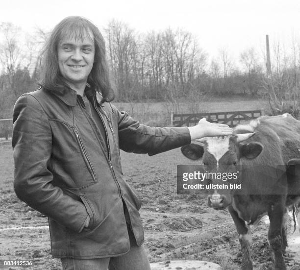 Der Sänger Udo Lindenberg 1975 bei einem Fototermin in Ostfriesland. Er steht in Lederjacke auf einer schlammigen Weide und deutet mit seinem Arm auf...