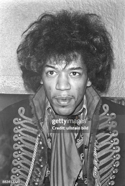 Der US-amerikanische Rock-Gitarrist und Sänger Jimi Hendrix. Er trägt ein Halstuch sowie eine reichverzierte Jacke mit hohem Kragen. .