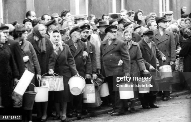 Hamburg: Flutkatastrophe 1962: Menschen stehen mit Eimern bei der Verteilung von Trinkwasser Schlange.