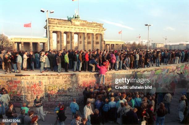 Mauerfall: Öffnung Grenze BRD/DDR: Menschen besteigen die Berliner Mauer vor dem Brandenburger Tor .