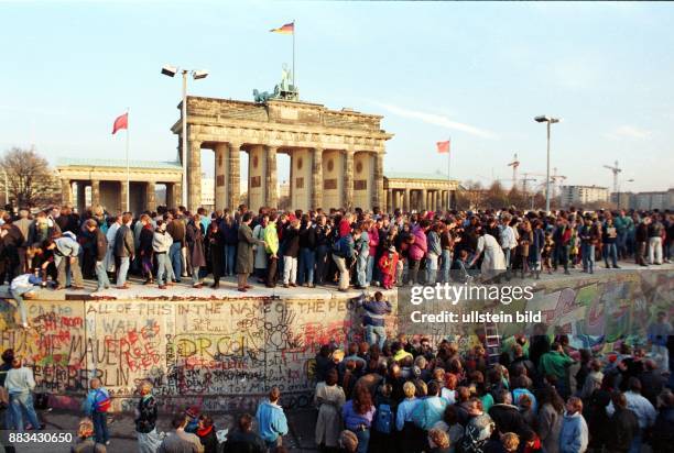 Deutschland / DDR, Berlin: Mauerfall. Menschen auf der Mauer am Brandenburger Tor. .