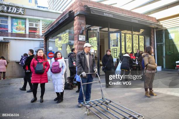 Citizens walk past a shop of Dongding wholesale market before its closing on November 30, 2017 in Beijing, China. The Dongding market, the last of 12...