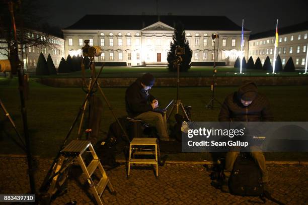 Press photographers sit at their laptop computers in near freezing weather outside Schloss Bellevue presidential palace, where inside the leaders of...