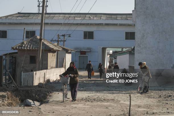 In a photo taken on November 22 people push bicycles along a street on the outskirts of Hamhung on North Korea's northeast coast. / AFP PHOTO / Ed...