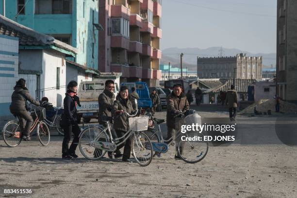In a photo taken on November 22 people push bicycles along a street in Hamhung on North Korea's northeast coast. / AFP PHOTO / Ed JONES