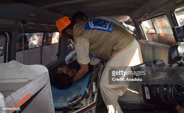 Pakistani rescuers shift an injured victim in a ambulance to take him to hospital following an attack on Peshawar Agricultural Training Institute by...