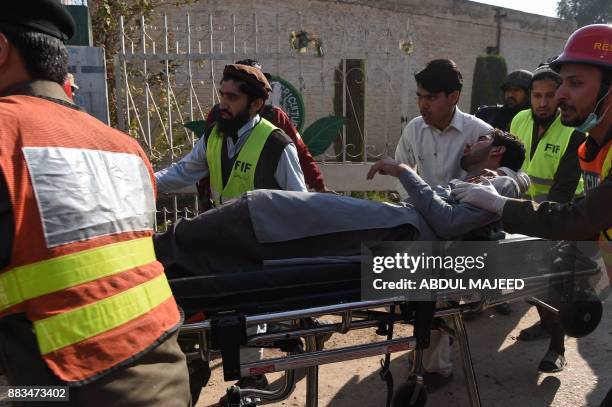 Pakistani volunteers move an injured student from an Agriculture Training Institute after an attack by Taliban militants in Peshawar on December 1,...