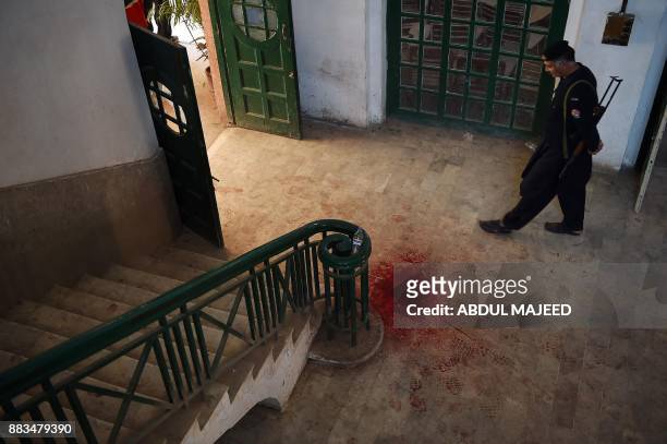 Pakistani policeman looks a blood-stained floor of an Agriculture Training Institute following an attack by Taliban militants in Peshawar on December...