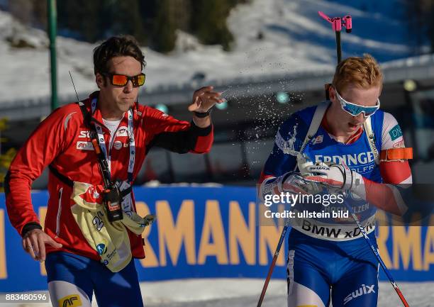 Ein Betreuer ueberreicht Johannes Thingnes Boe ein Getraenk beim Laufen waehrend dem 20km Einzelrennen der Herren bei der IBU Biathlon...