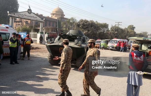 Pakistani security forces and rescuers are seen outside Peshawar Agricultural Training Institute which was attacked by Taliban militants, in the...