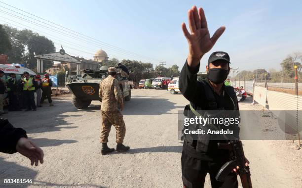 Pakistani security forces and rescuers are seen outside Peshawar Agricultural Training Institute which was attacked by Taliban militants, in the...