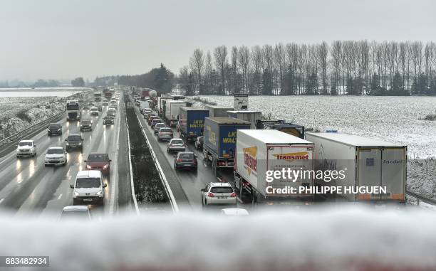 Cars and trucks drive slowly on the A1 highway in Templemars, northern France, following wet snowfall, or sleet, on December 1, 2017. / AFP PHOTO /...