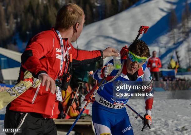 Ein Betreuer ueberreicht Ole Einar Bjoerndalen ein Getraenkt beim Laufen waehrend dem 20km Einzelrennen der Herren bei der IBU Biathlon...