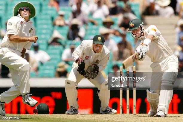 Australian batsman Damien Martyn slams a ball at South African fieldsman Neil McKenzie as wicketkeeper Mark Boucher looks on on the second day of the...