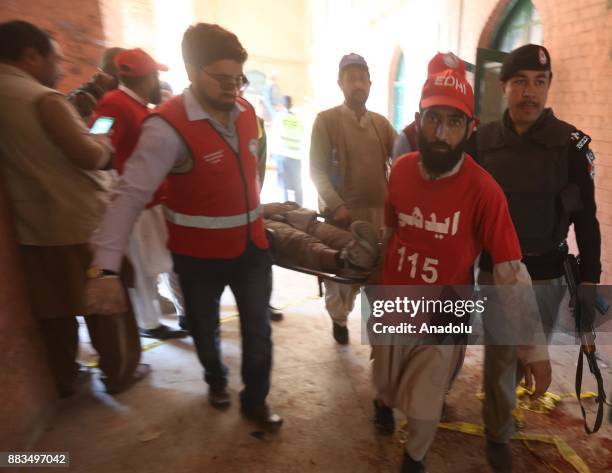 Pakistani rescuers carry the body of a Taliban militant at Peshawar Agricultural Training Institute which was attacked by Taliban militants, in the...