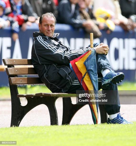 Huub Stevens - Trainer, Hamburger SV, Holland: sitzt auf einer Bank, daneben ein Regenschirm