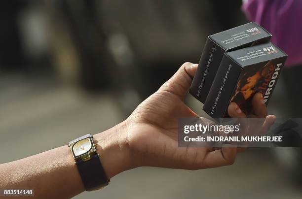 An Indian NGO volunteer holds packets of condoms for distribution at street corner on the occasion of World Aids Day in Mumbai on december 1, 2017. /...