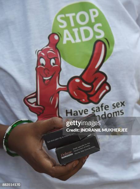 An Indian NGO volunteer holds packets of condoms for distribution at street corner on the occasion of World Aids Day in Mumbai on december 1, 2017. /...