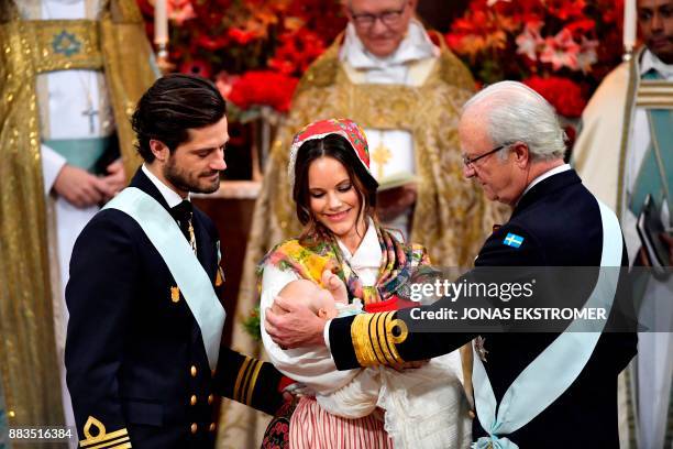 Prince Carl Philip, princess Sofia and King Carl Gustaf of Sweden attend to baby with prince Gabriel during his christening in Drottningholm Palace...