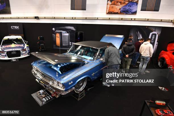 Visitors look at a Ford Galaxie classic car on December 1, 2017 during the 'Essen Motor Show' fair in Essen, western Germany. According to the...