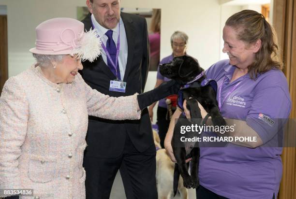 Britain's Queen Elizabeth II is introduced to 12 week old Labrador puppy 'Flint' by her trainer Ruth Narracott as she tours the facilities during a...