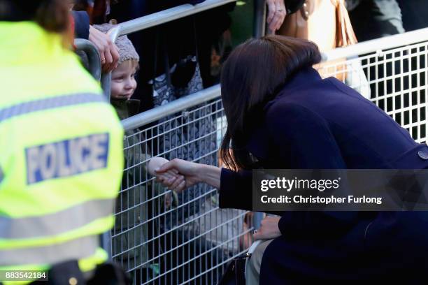 Meghan Markle shakes the hand of a child as she departs Nottingham Contemporary on December 1, 2017 in Nottingham, England. Prince Harry and Meghan...