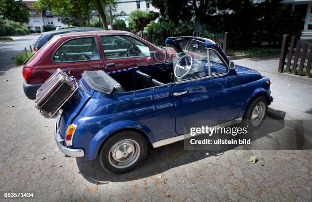 Vintage Fiat 500 city car, convertible with suitcase mounted on the rear luggage rack.