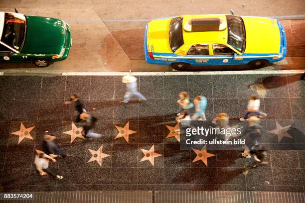 Passers-by walking at the Hollywood Boulevard, from a bird's eye view, with motion blur.