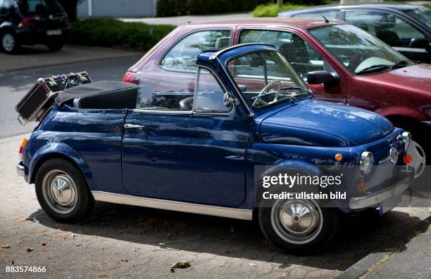 Vintage Fiat 500 city car, convertible with suitcase mounted on the rear luggage rack.