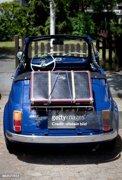 Vintage Fiat 500 city car, convertible with suitcase mounted on the rear luggage rack.
