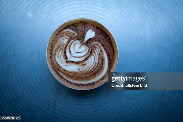 The barista fills coffee and milk froth in the cup and makes it look like the texture of a leaf, in a cafe in Ginza.