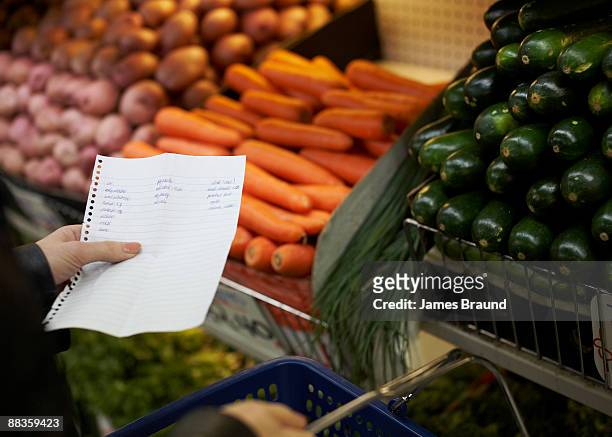 hand holding shopping list in market - shopping list stock pictures, royalty-free photos & images