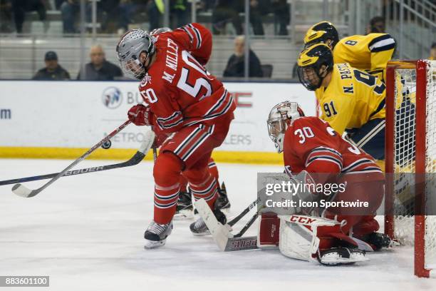 Ohio State Buckeyes defenseman Matt Miller tries to deflect the puck while Ohio State Buckeyes goalie Sean Romeo guards the goal and Michigan...