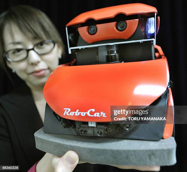 An employee of Japan's robot venture ZMP shows off a 1/10-scale platform for automobile reseach and development "RoboCar Z" during a press conference...