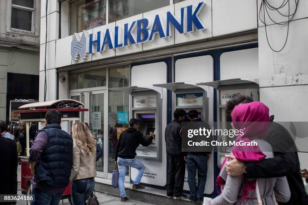 People walk past a branch of Turkish bank HalkBank on December 1, 2017 in Istanbul, Turkey. The trial of Mr. Reza Zarrab, an Iranian-Turk who ran a...