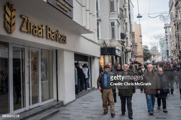 People walk past a branch of Turkish bank Ziraat Bank on December 1, 2017 in Istanbul, Turkey. The trial of Mr. Reza Zarrab, an Iranian-Turk who ran...