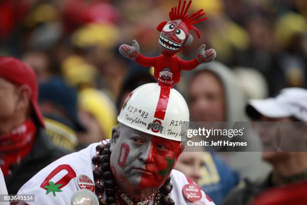 Closeup of Ohio State face painted fan in stands honoring former player Terry Glenn on helmet after his passing during game vs Michigan at Michigan...