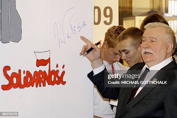 Nobel peace prize laureate and former Polish President Lech Walesa points at his signature at the "Ernst-Reuter-Plakette" awards ceremony on June 9,...