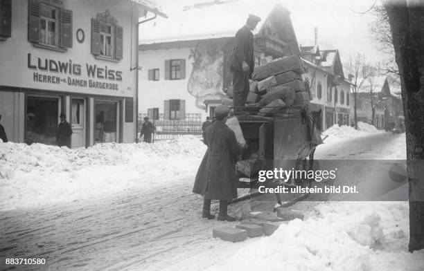 Postmitarbeiter liefern Pakete auf einem Schlitten in einer verschneiten Siedlung aus Originalaufnahme im Archiv von ullstein bild