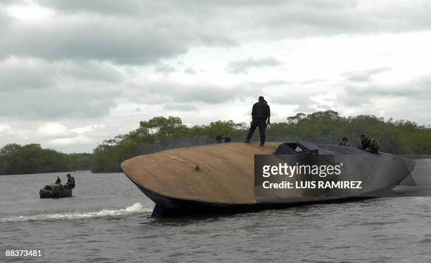 Colombian Navy personnel stand guard over a midget submersible in Playa del Vigia, Narino Department on June 4, 2009. According to the Colombian...