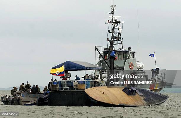 Colombian Navy patrol boat stays alogside a seized midget submersible in Playa del Vigia, Narino Department on June 4, 2009. According to the...