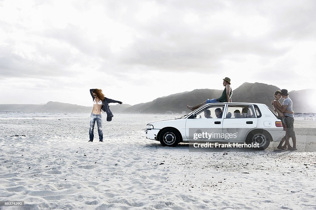 Teenagers with car on beach