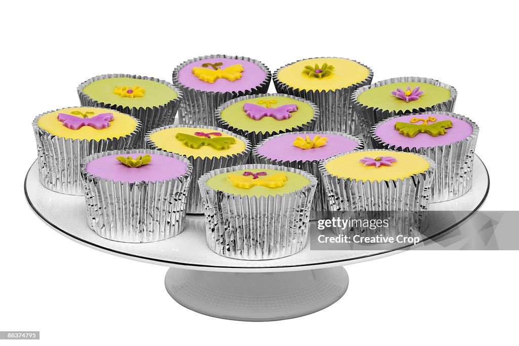 Pink, yellow, and green cup cakes on a white cake 